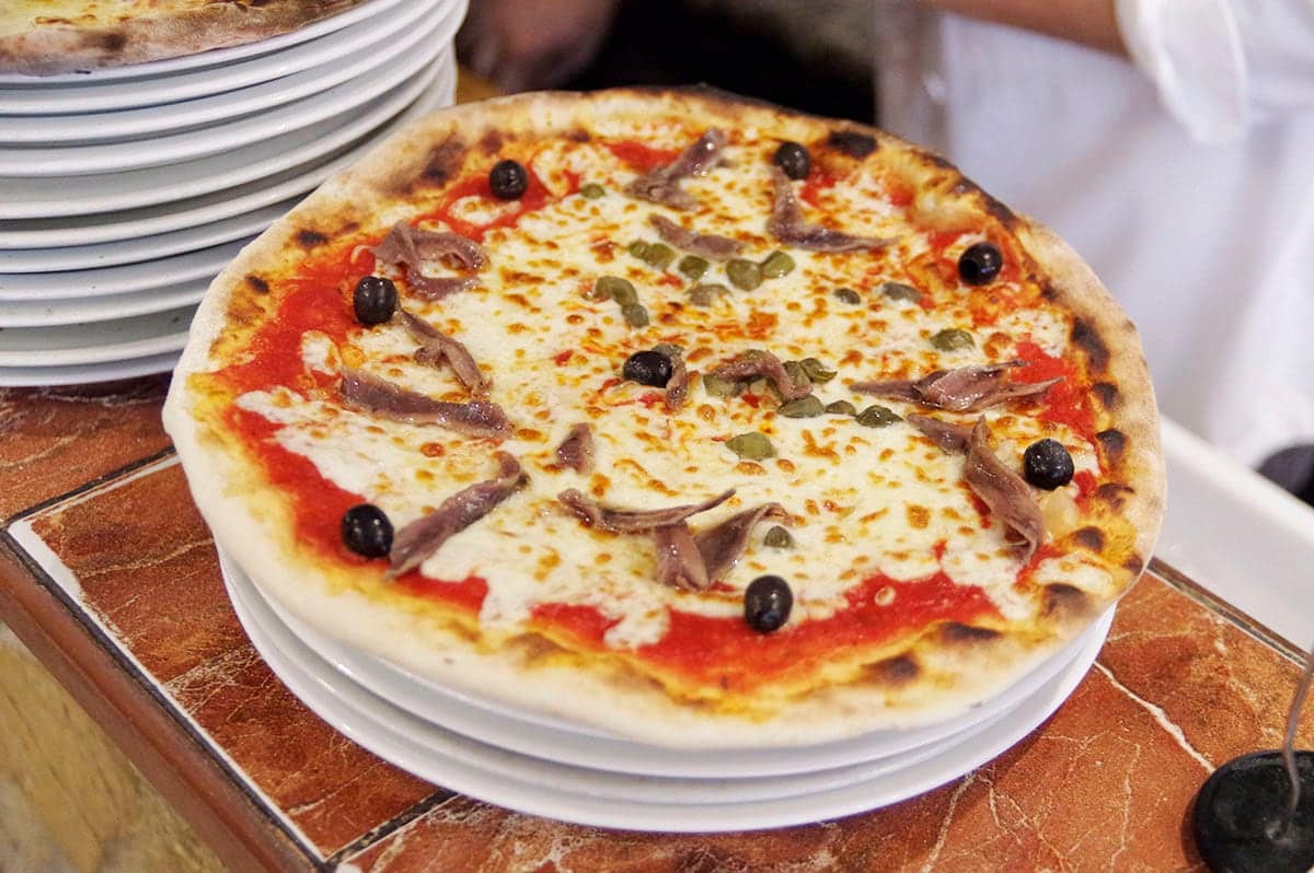 Pizza Napolitaine : mozzarella, anchois, câpres et olives noires.